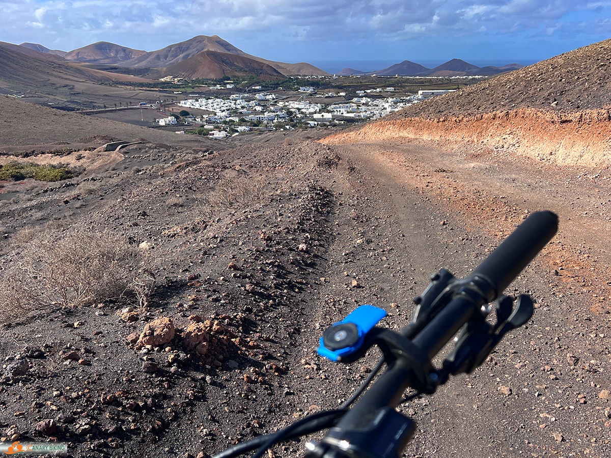 Deel van stuur van EMTB op gravelweg met uitzicht op Yaiza en vulkanen in Lanzarote