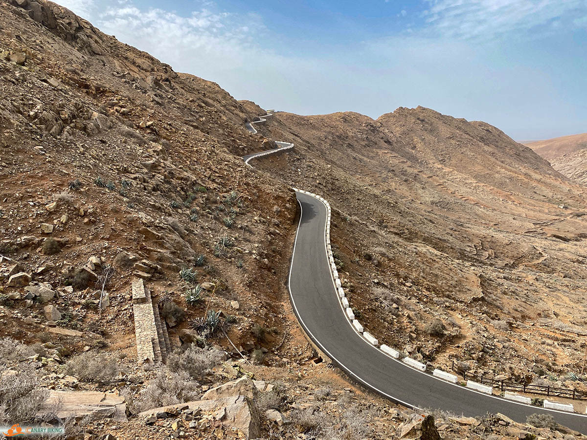 Slingerende weg door woestijnachtig gebergte op zonnige dag